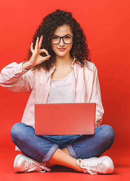 Online English School in London and Worldwide student on computer with red backdrop using OK sign